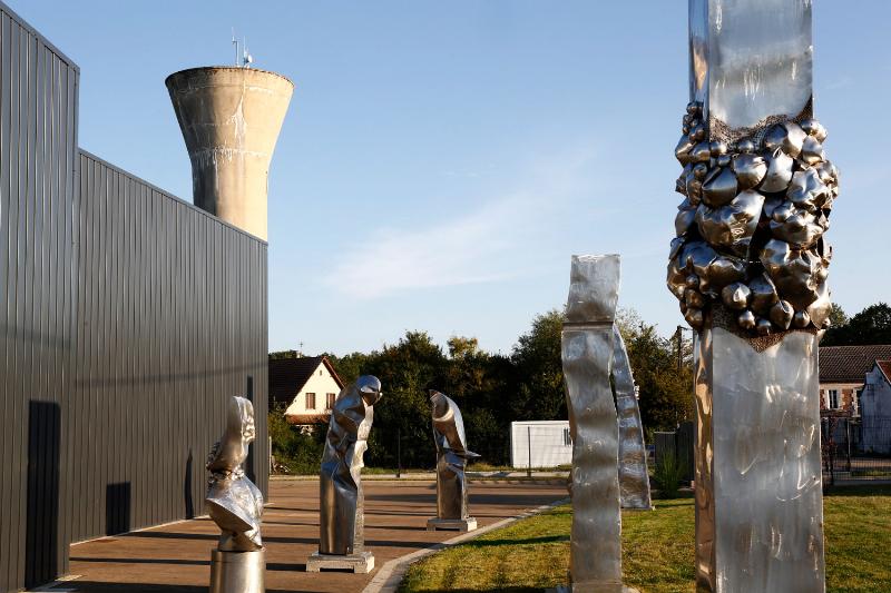 Un artiste en plein travail dans son atelier, sculptant du métal avec des outils de soudure et de meulage.