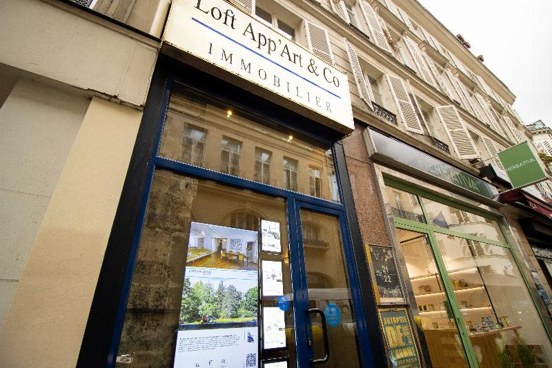 Vue d'un atelier d'artiste spacieux et lumineux dans une résidence d'art française, avec de grandes fenêtres donnant sur un jardin et des outils d'art contemporain.