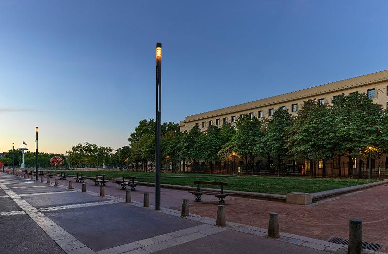 Installation lumineuse contemporaine de mobilier urbain la nuit, éclairant une place