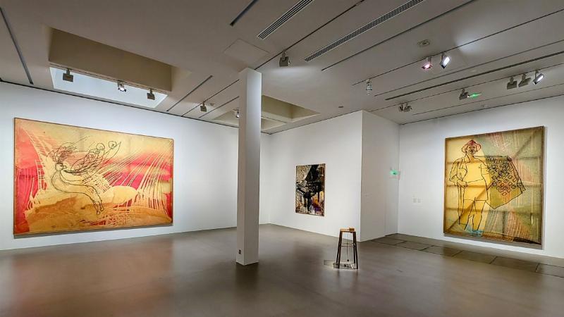 Une sculpture de pingouin abstraite et colorée installée dans une galerie d'art moderne, avec des visiteurs l'admirant.