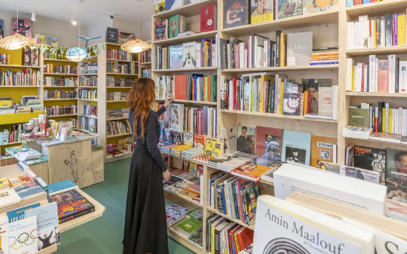 Jeune femme lisant un livre de littérature française contemporaine dans une librairie indépendante parisienne