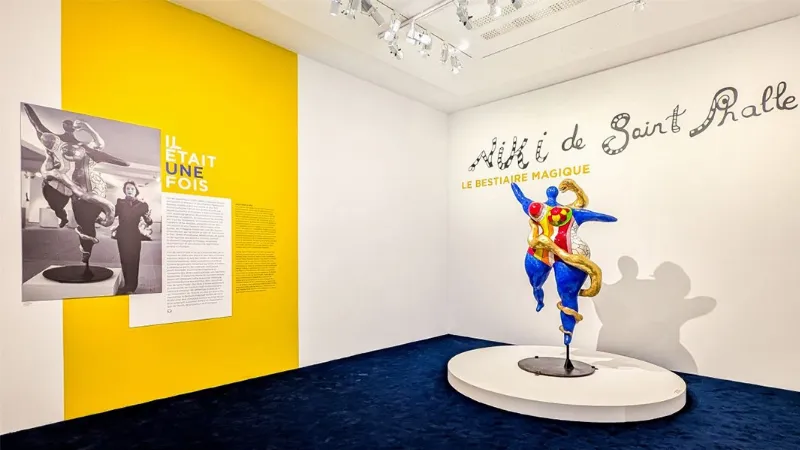Niki de Saint Phalle travaillant sur une sculpture colorée dans son atelier, entourée de ses œuvres.