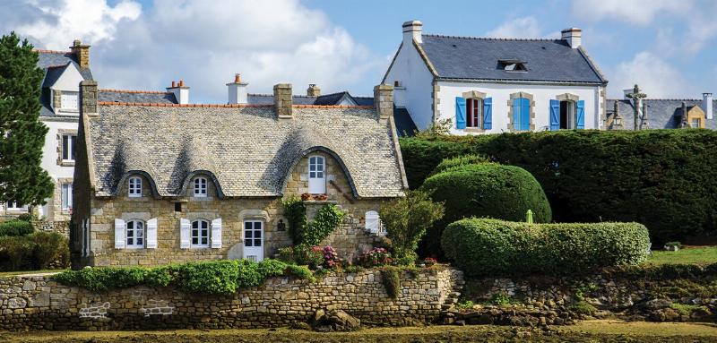 Façade de maison française en brique peinte en blanc éclatant, avec volets bleus