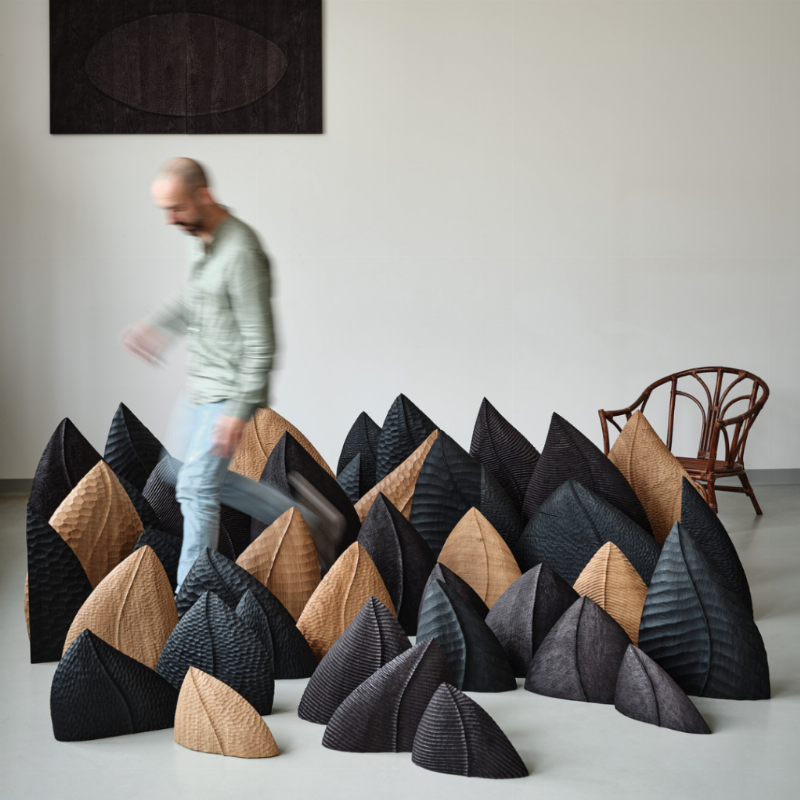 Sculpteuse française contemporaine travaillant sur une statue bois dans son atelier, outils à la main, lumière naturelle.