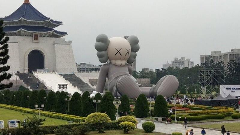 Sculpture KAWS "Companion" monumentale dans un paysage urbain moderne avec des gratte-ciel