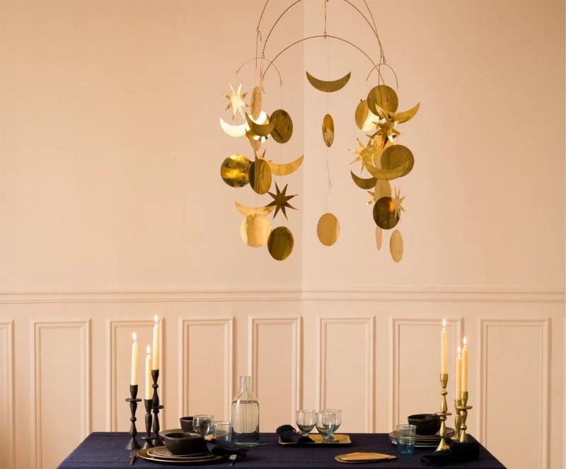 Une sculpture suspendue contemporaine jouant avec la lumière et les ombres sur un mur clair