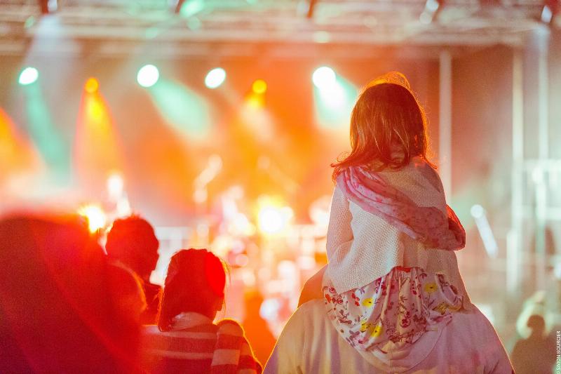 Une ambiance de festival en plein air, avec des gens dansant joyeusement sur de la musique contemporaine