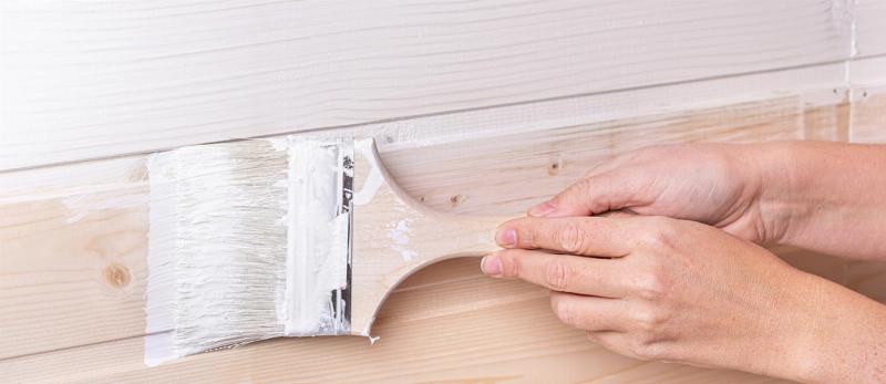 Application méthodique de peinture sur une surface en bois exotique extérieur à l'aide d'un pinceau