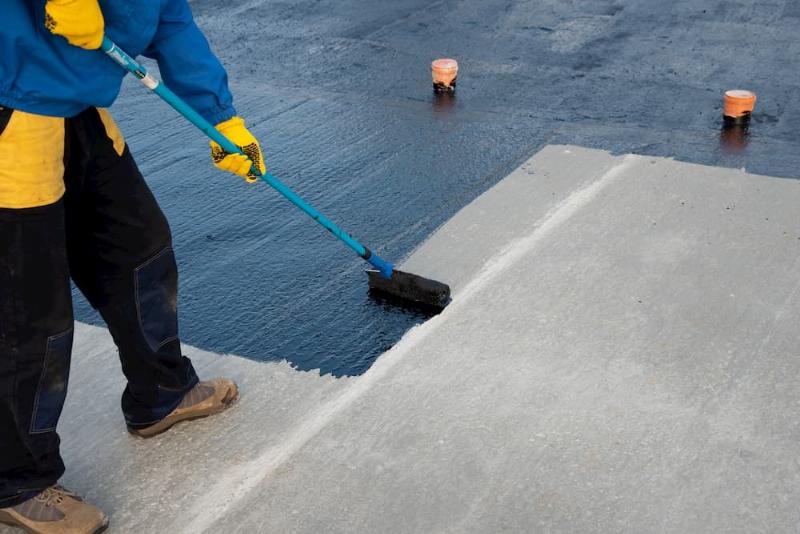 Application méticuleuse de la première couche de peinture époxy sur un sol de garage par un professionnel