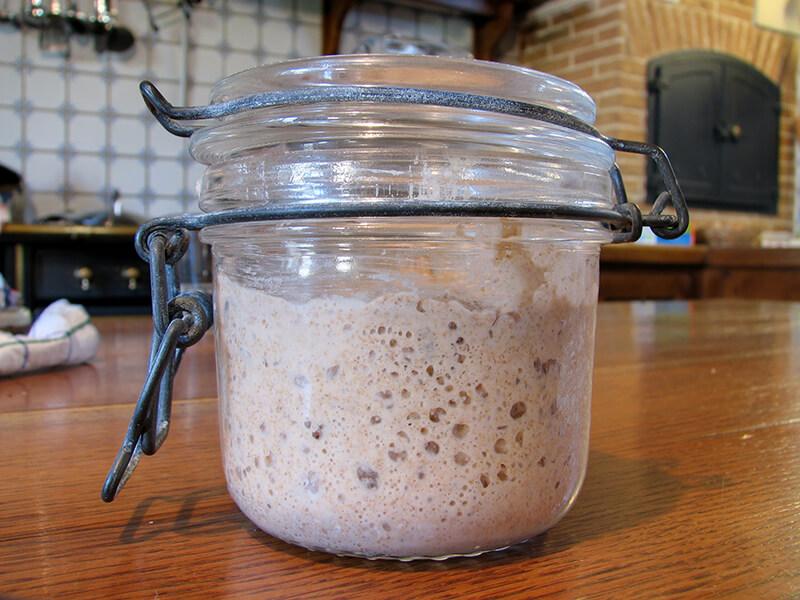 Un artisan appliquant la peinture à la farine sur une surface en bois avec un pinceau traditionnel, un geste de savoir-faire