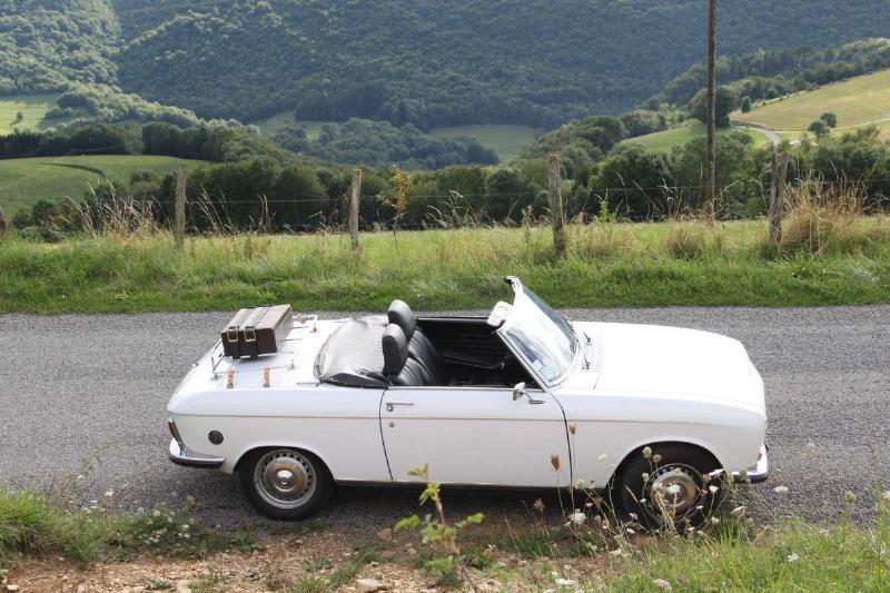 Application méthodique de la peinture noire sur une jante avec un pistolet pulvérisateur, dans un atelier automobile bien éclairé.