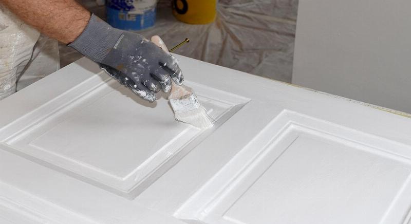 Application méticuleuse de peinture sur une porte intérieure française avec un pinceau fin