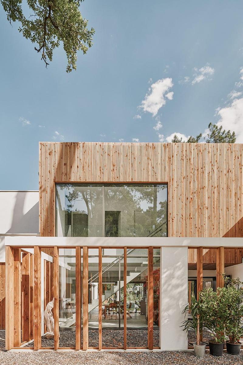 Une façade d'architecture moderne blanche minimaliste, baignée de lumière naturelle, avec des lignes épurées et des fenêtres larges.