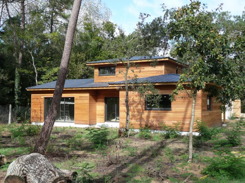 Petite maison moderne avec bardage bois et grandes ouvertures vitrées, s'intégrant au paysage