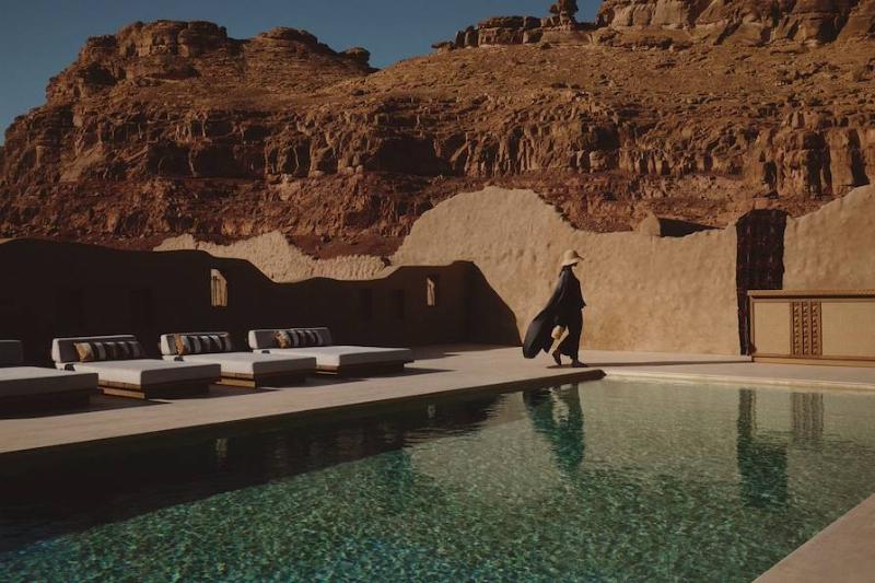 Une personne assise sur une terrasse moderne en Arizona, contemplant le paysage désertique au coucher du soleil