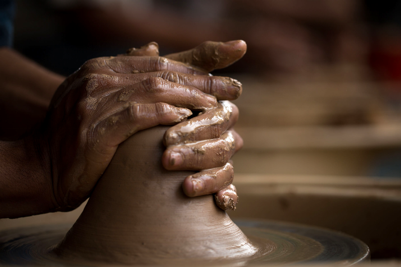 Artiste contemporain modelant une sculpture buste femme argile dans son atelier, lumière naturelle