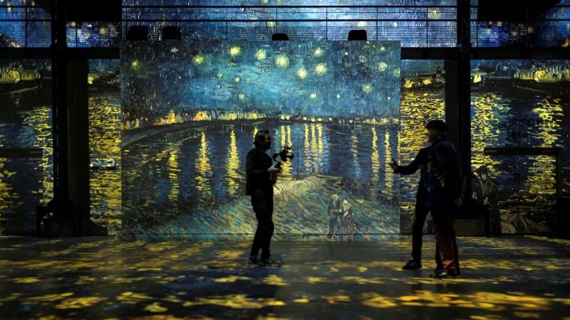Vue intérieure de l'Atelier des Lumières avec une projection immersive de l'œuvre de Van Gogh, couleurs vives, public