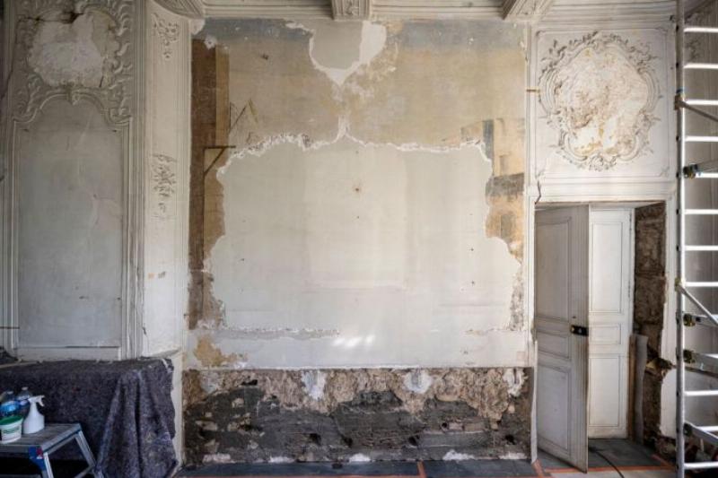 Un coin d'atelier d'artiste français avec des tubes de peinture, des pinceaux dans un pot, et une esquisse d'un souvenir sur un chevalet, baigné par la lumière douce d'une fenêtre.
