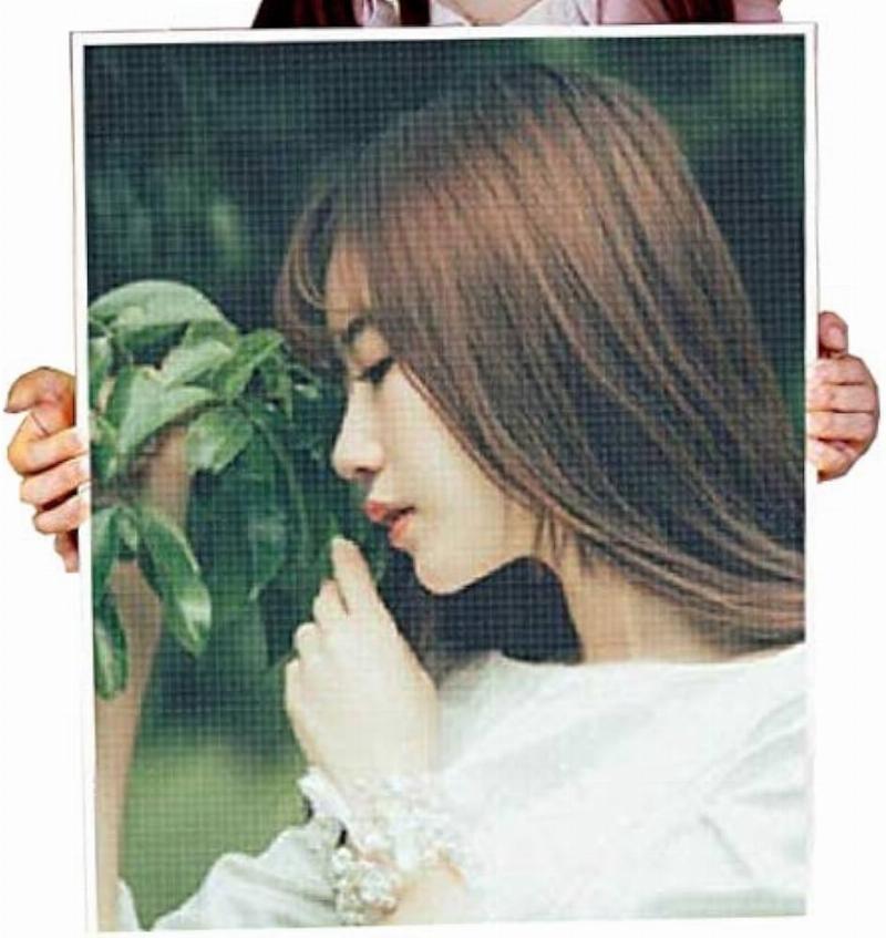 Une toile de broderie diamant en cours de réalisation, montrant les perles scintillantes et les symboles sur la toile.