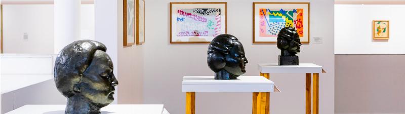 Sculpture d'une femme portant une valise ouverte, symbole de voyage et de vie.