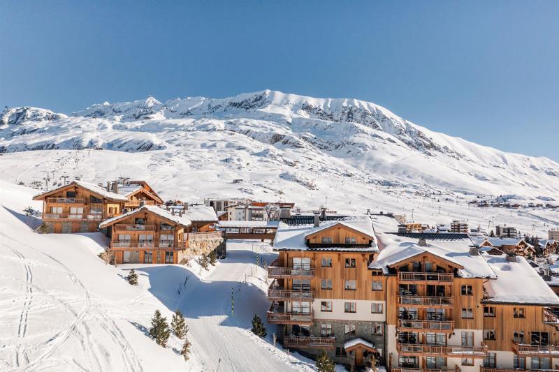 Architecture moderne de montagne avec façades en bois et grandes baies vitrées, offrant une vue sur les sommets enneigés