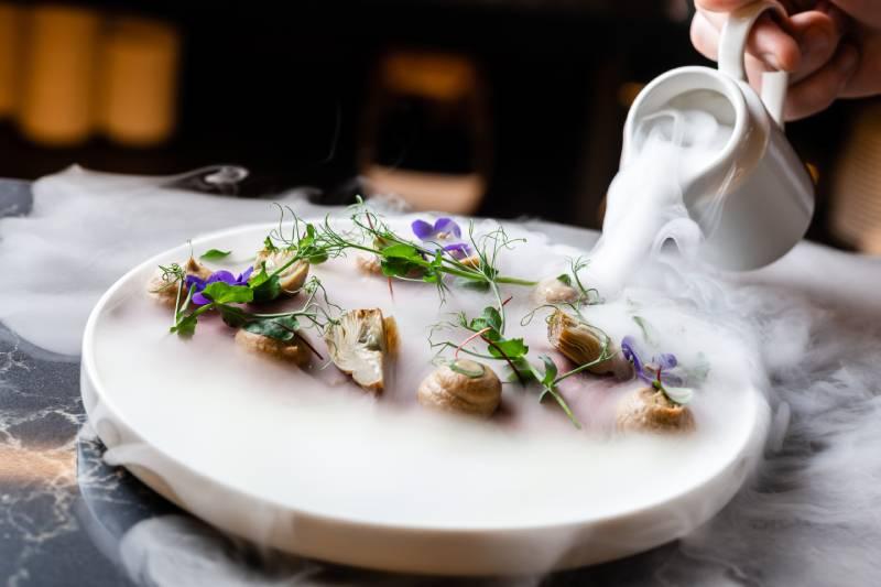 Chef travaillant avec des ingrédients dans une cuisine moderne, expérimentant des textures et des formes innovantes.