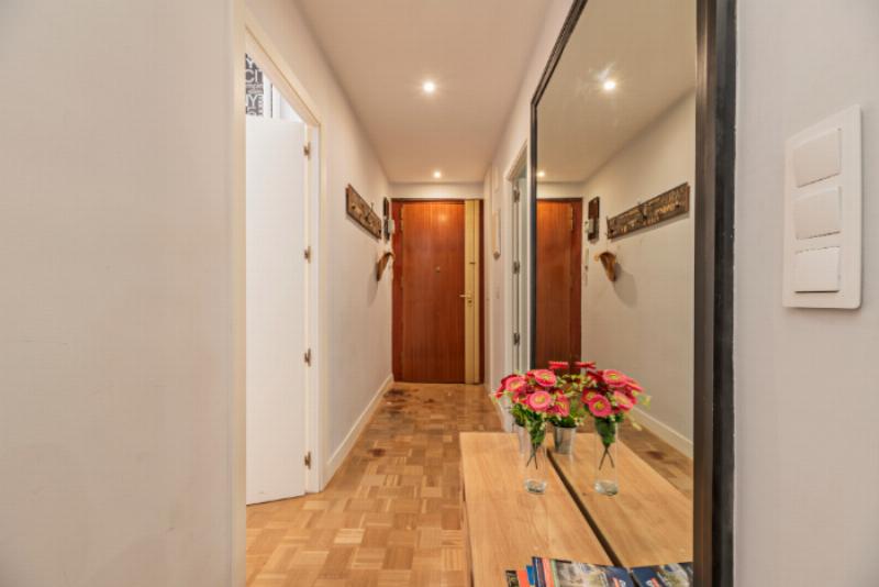 Un couloir étroit et sombre transformé avec une peinture claire, un grand miroir mural et des appliques élégantes