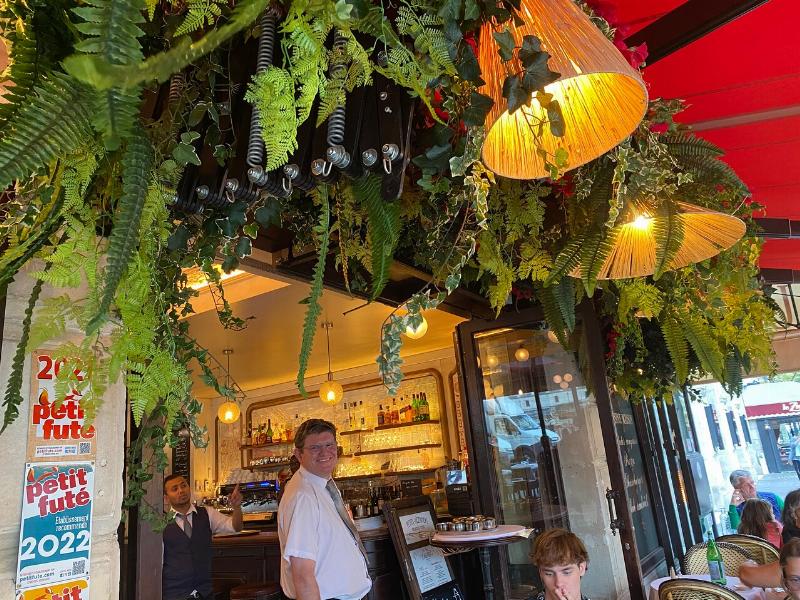 Intérieur chaleureux d'un bistro parisien abordable près de Notre-Dame, montrant une cuisine ouverte et des plats généreux, mettant en valeur un restaurant pas cher Notre-Dame de Paris