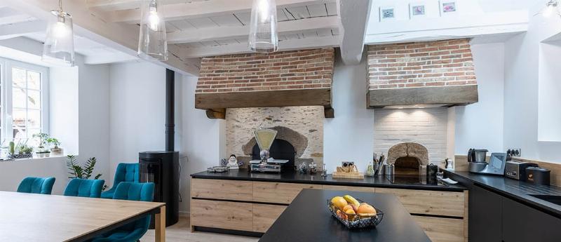 Une cuisine en bois peinte dans un style français chic, avec des tons doux, des éléments décoratifs élégants et une ambiance raffinée.