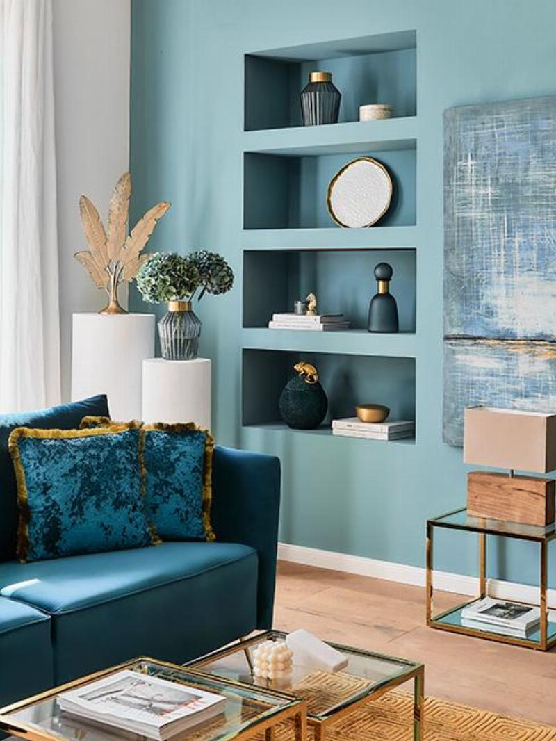 Alt text: Inspiration déco salon avec murs vert gris foncé, canapé en velours et accents dorés