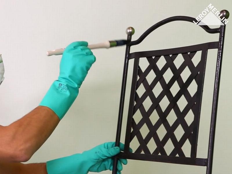 Application de décapant chimique sur une grille en fer forgé pour enlever la peinture ancienne avant rénovation