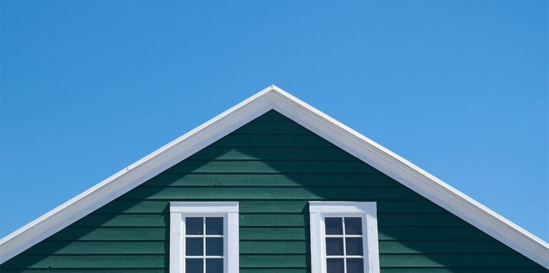 Une façade jaune ocre d'une maison ancienne en Provence, sous un soleil éclatant, avec des volets bleus