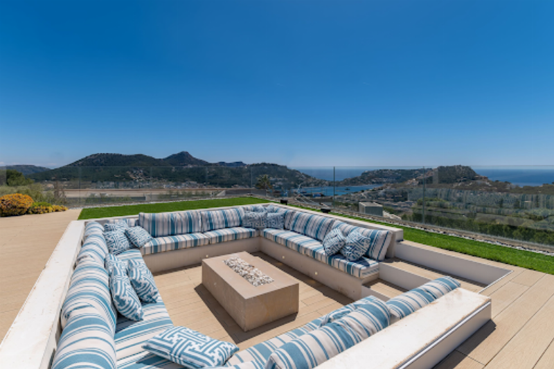 Façade d'une villa résidentielle moderne intégrant des éléments de pierre naturelle et de verre, avec une toiture plate, située dans un jardin paysager méditerranéen en France, symbolisant l'harmonie avec la nature.