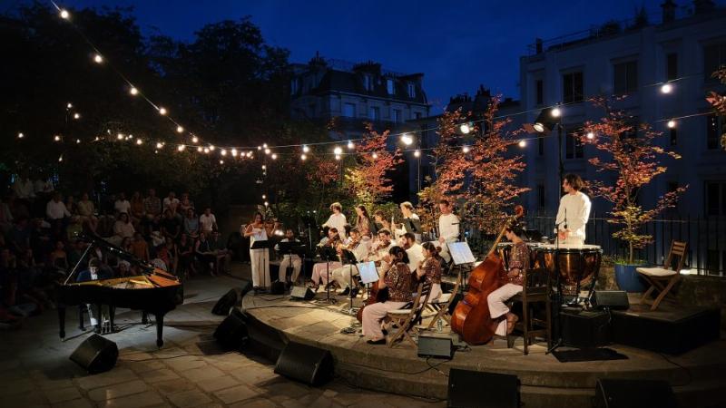 Festival de musique classique en France 2023, scène en plein air avec orchestre sous un ciel étoilé, public attentif