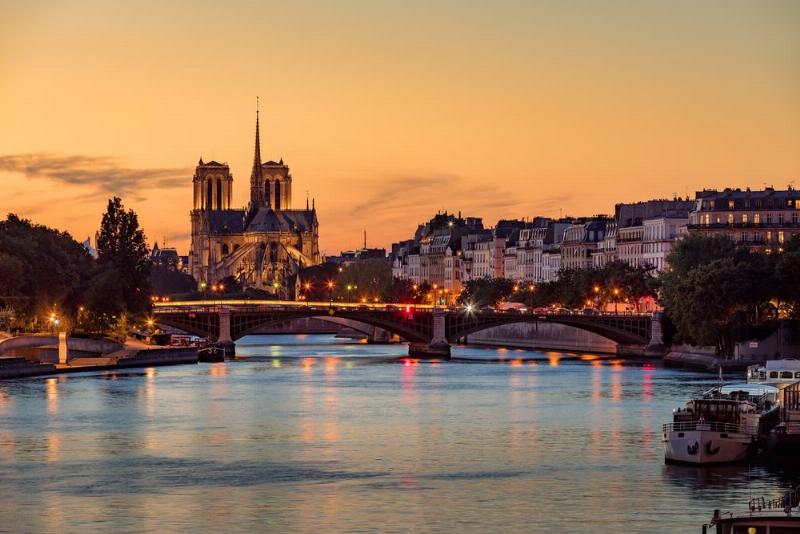 Scène animée de la Fête de la Musique dans une rue parisienne bondée au coucher du soleil.