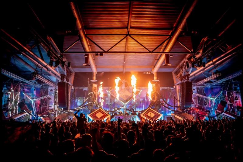 Scène d'un festival de musique électronique français avec des lumières vibrantes et une foule énergique