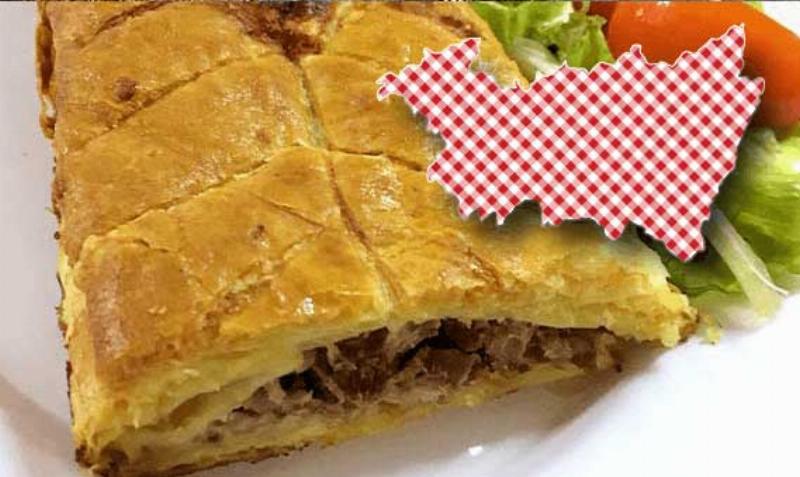 Un plat traditionnel vosgien fumant, avec des pommes de terre et du lard, servi sur une table en bois rustique dans un restaurant typique de Ventron.