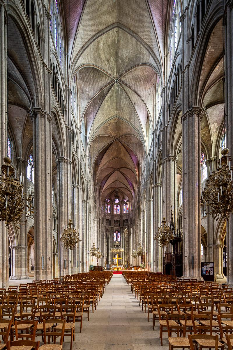 Intérieur d'une cathédrale gothique en France, lumière filtrée par les vitraux anciens