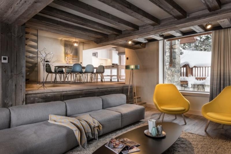 Intérieur de chalet moderne avec mobilier design épuré, cheminée centrale et vue sur montagne