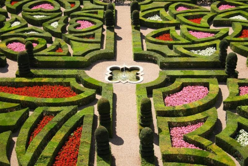 Un jardin d'art français classique avec des parterres géométriques, des fontaines et des sculptures, reflet de la grandeur du XVIIe siècle.