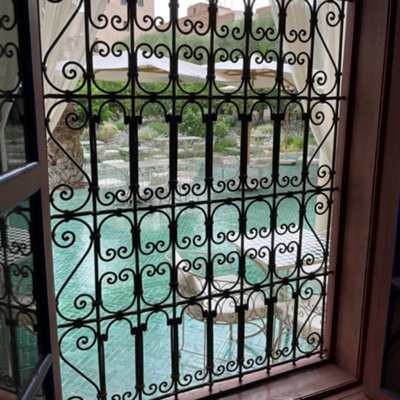 Vue du Jardin Majorelle mettant en scène le célèbre bleu Majorelle sur les bâtiments et les bassins, avec une végétation luxuriante.