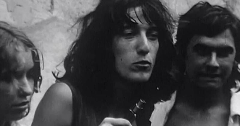 Jeune manifestant français jouant de la guitare lors des événements de Mai 68, symbolisant la musique et culture 68