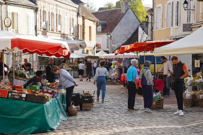 Un marché provençal animé avec des étals de produits frais, fruits, légumes, fromages, ambiance locale, coutumes régionales