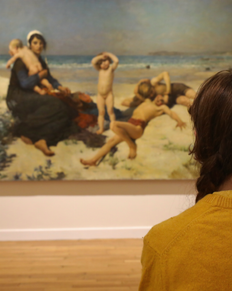 Des visiteurs au Musée d'Orsay observant une oeuvre d'art connu simple, un moment de contemplation devant un chef-d'œuvre français.