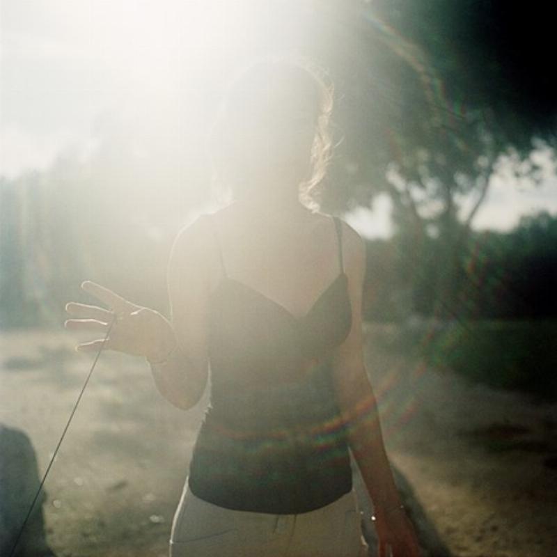 Une femme souriante écoutant de la musique avec des écouteurs, reflétant la joie et la détente. L'arrière-plan évoque une ambiance parisienne douce.