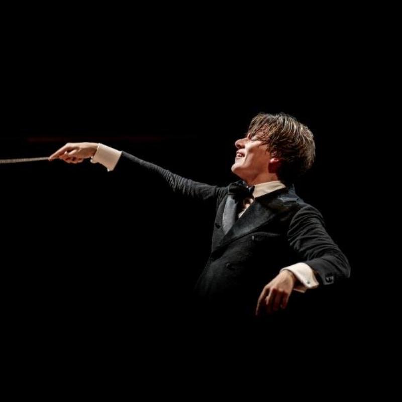 Un orchestre symphonique interprétant une pièce de musique moderne classique française, avec des musiciens concentrés et des jeux de lumière