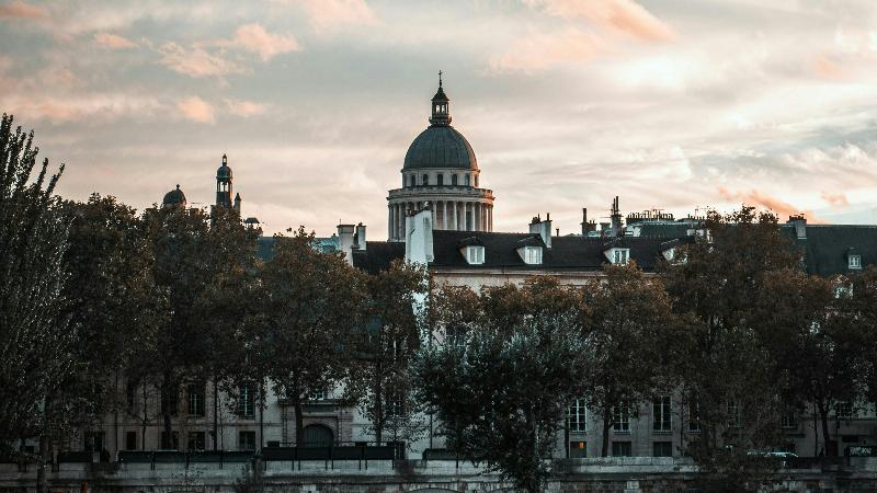 Ambiance animée du Quartier Latin près de Notre-Dame de Paris, avec un café en terrasse et des passants.