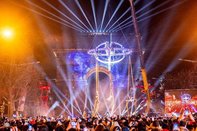 Illumination des Champs-Élysées à Paris pendant les fêtes de Noël, avec la foule et l'Arc de Triomphe en arrière-plan