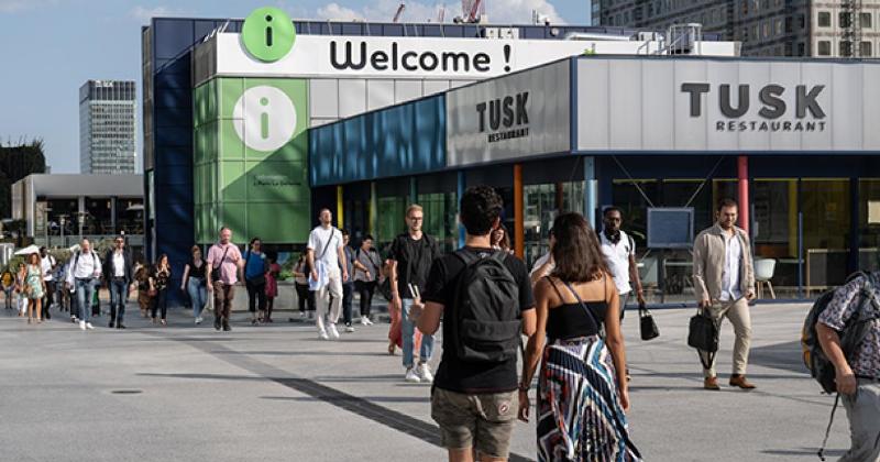 La pyramide du Louvre et le palais historique sous un ciel bleu clair, avec des visiteurs se promenant sur la place. Tours de Paris.