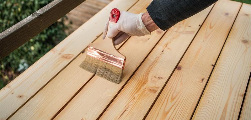 Une sélection de pots de peinture acrylique de haute qualité pour bardage bois, dans des teintes naturelles et élégantes, posés sur une surface en bois
